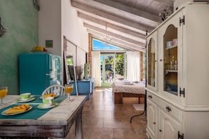 Une cuisine chaleureuse avec une table à manger dressée pour le petit-déjeuner, un réfrigérateur bleu et une vue sur la pièce adjacente.