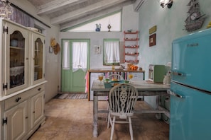 A kitchen with a dining table, chairs, a refrigerator, and a window with curtains. - Tiny House With Private Pool Kostrena (Kostrena)