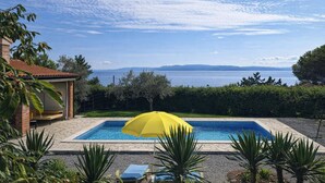 A swimming pool with a yellow umbrella, surrounded by greenery and a view of the sea. - Tiny House With Private Pool Kostrena (Kostrena)
