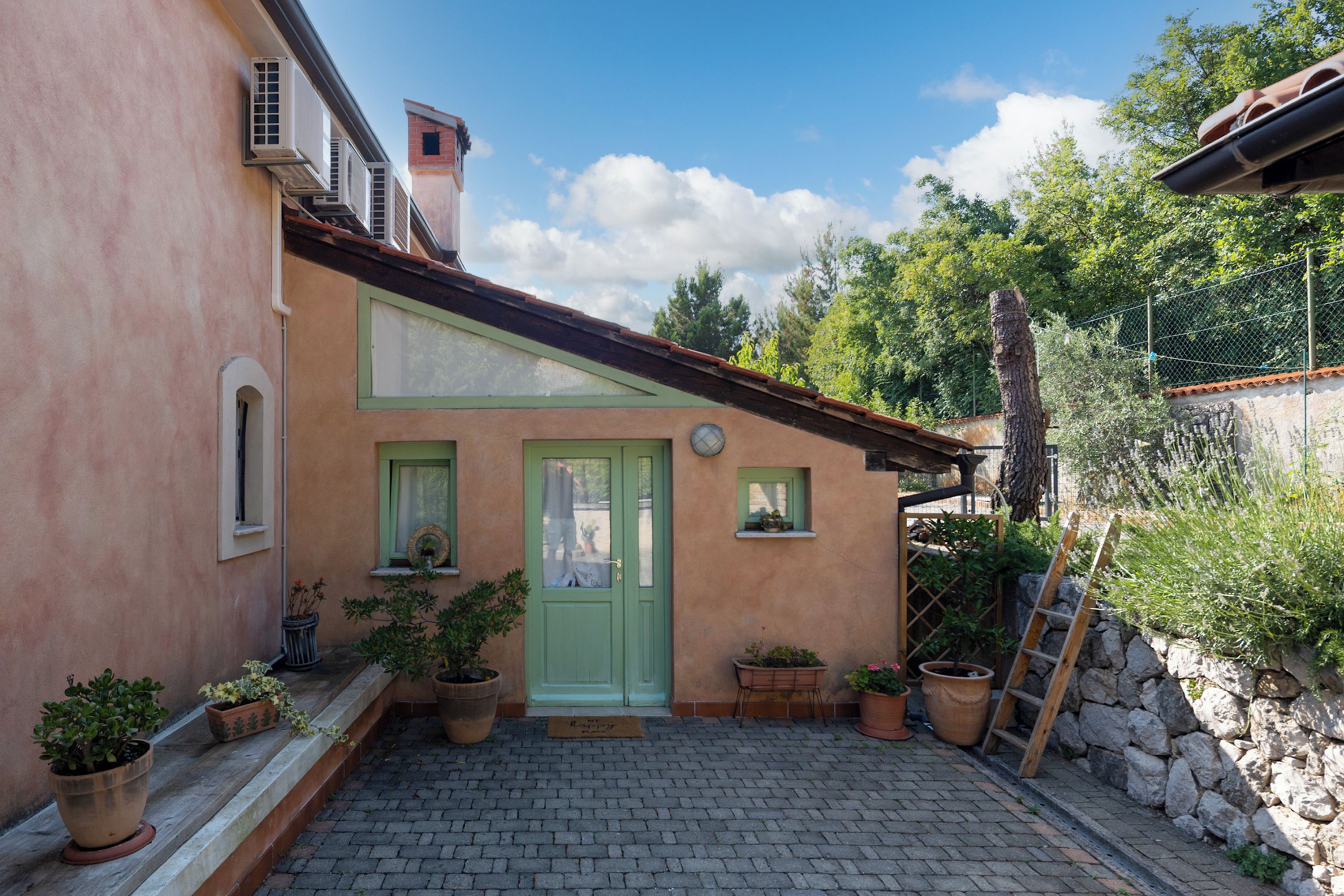 A building with a green door, potted plants, and a stone wall.