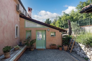 A building with a green door, potted plants, and a stone wall. - Tiny House With Private Pool Kostrena (Kostrena)