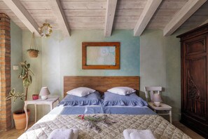 A bedroom with a wooden headboard, a bed with blue bedding, two bedside tables with lamps, a potted plant, and a wooden wardrobe. - Tiny House With Private Pool Kostrena (Kostrena)