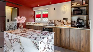 A modern kitchen with a marble island, wooden cabinets, and a red ceiling.