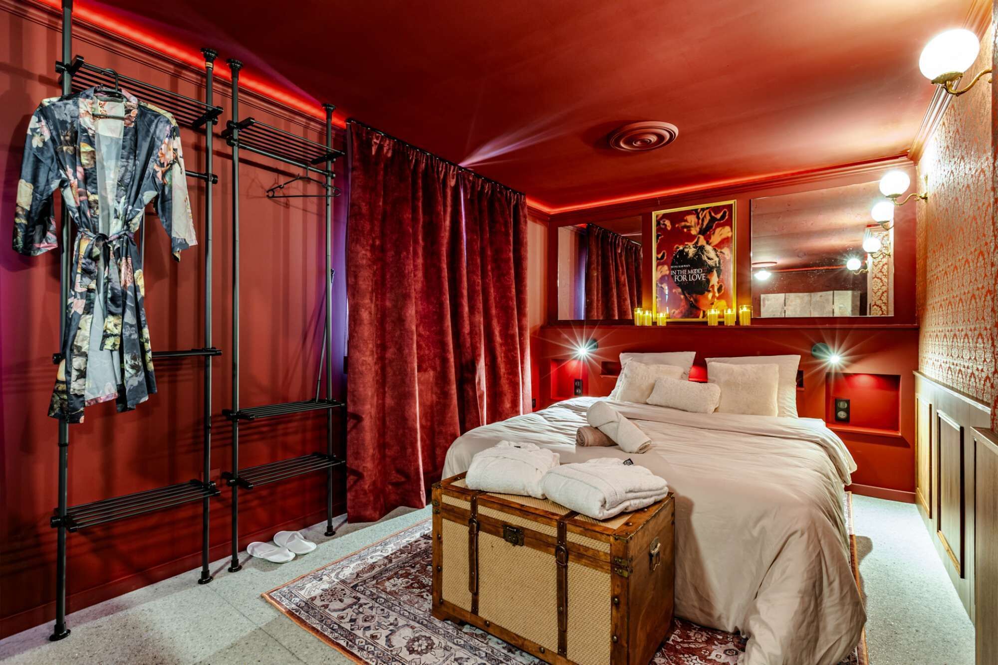 Een hotelkamer met een bed, een koffer, een droogrek en een spiegel.