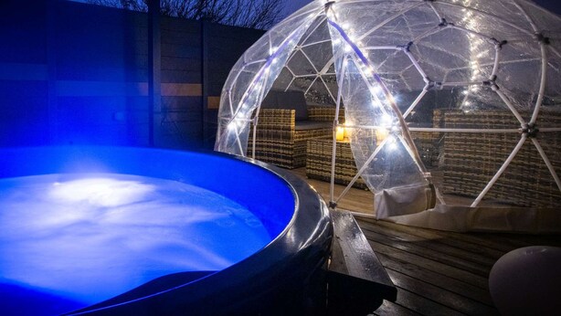 A geodesic dome structure with a hot tub in the foreground.