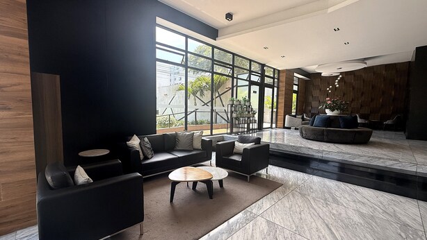 A modern lobby with a black sofa, round tables, and a large window.