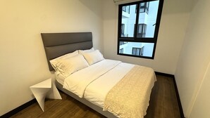A bedroom with a bed, a window, and a wooden floor.
