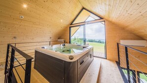 Une cabane en bois dotée d’un bain à remous, de grandes fenêtres et offrant une vue sur l’extérieur.