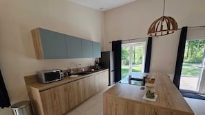A modern kitchen with wooden cabinets, a built-in microwave, and a large island with a sink. - Létendart (Saint-Quentin-en-Tourmont)