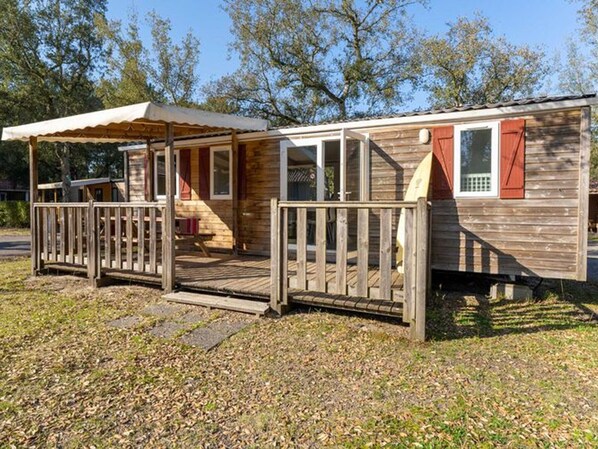Une cabane en bois dotée d’un porche couvert et d’une petite terrasse.