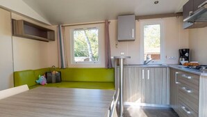 A compact kitchen with a green sofa, a dining table, and a coffee machine.