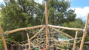 A playground structure made of ropes and wooden poles.