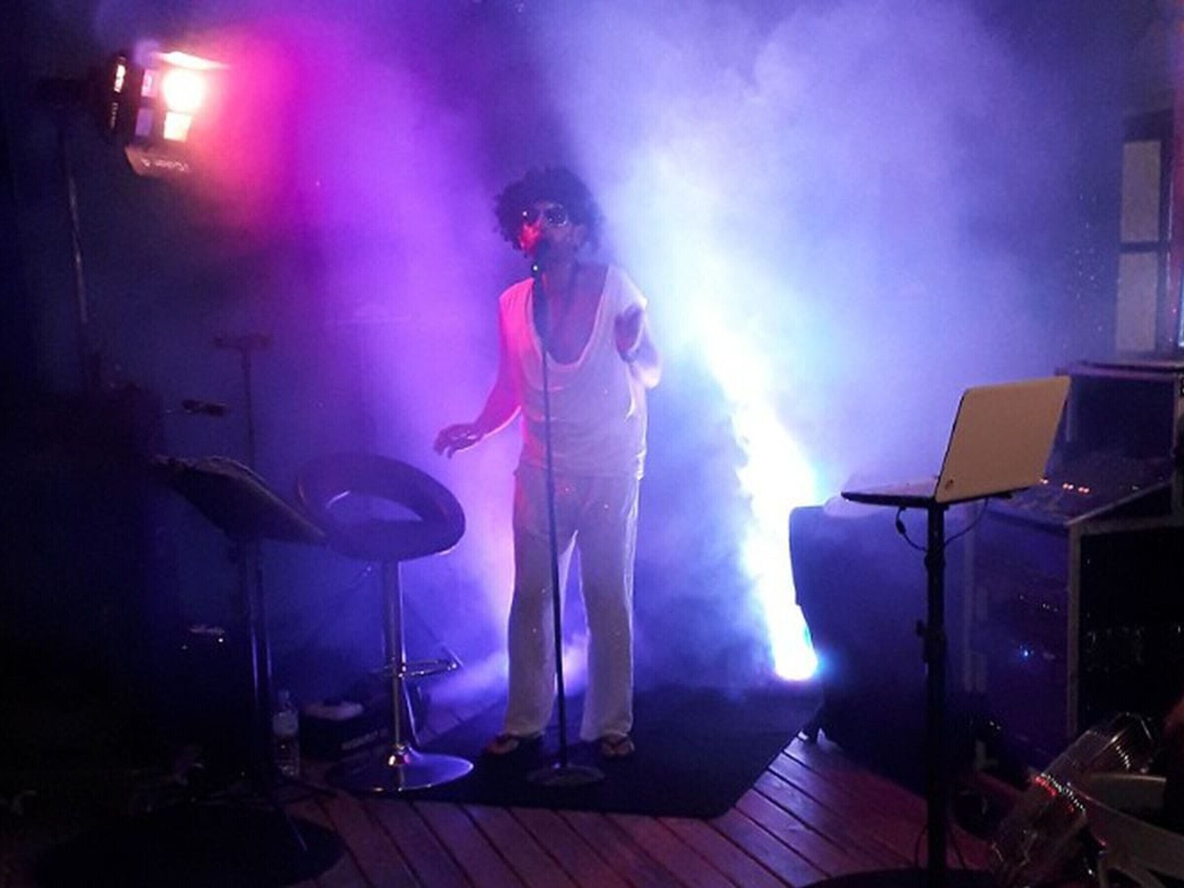 A person standing on a stage with a laptop and a microphone stand.