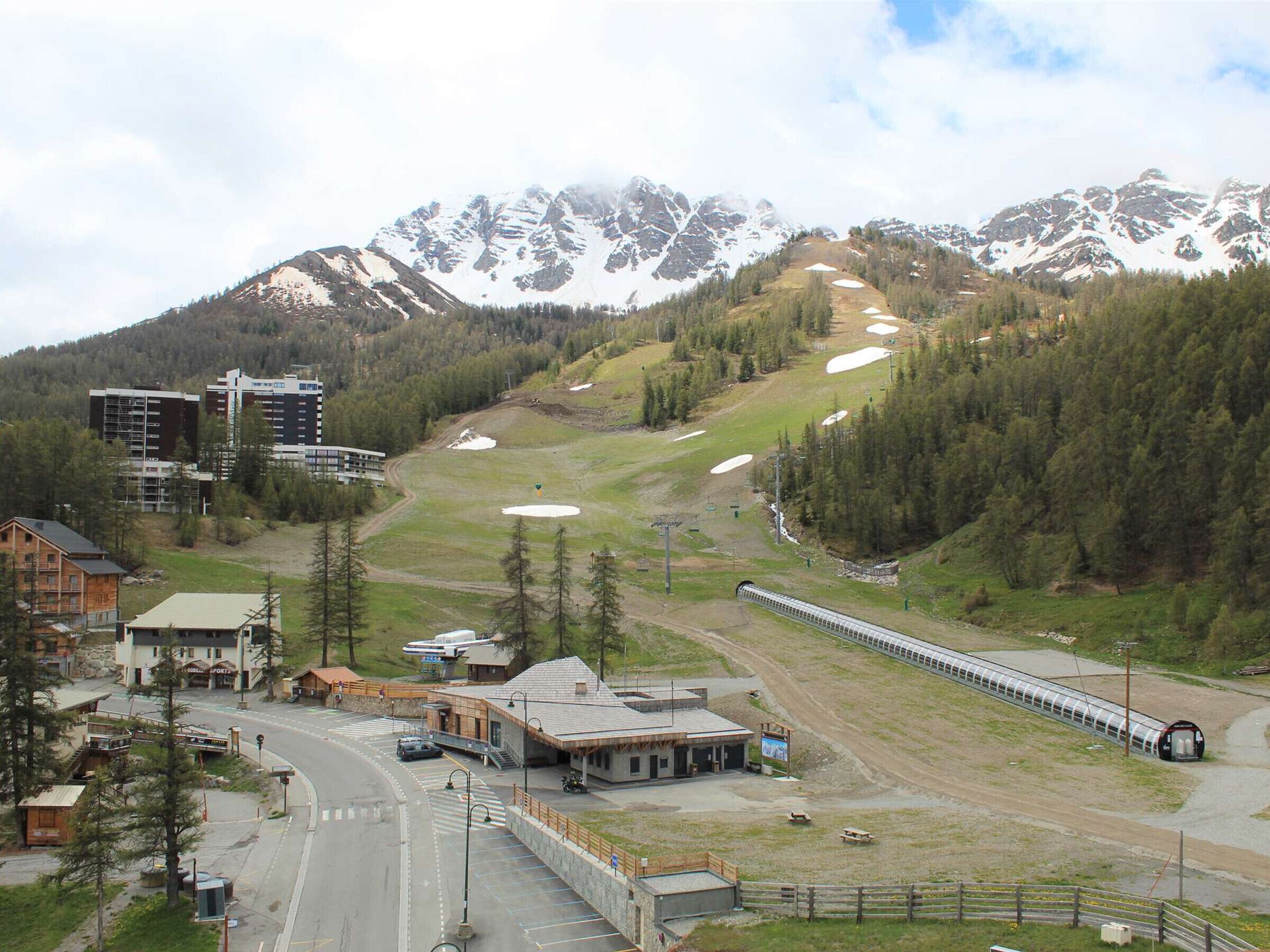 A mountain town with a train station, buildings, and a road.