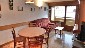 A cozy dining area with a round table, wooden chairs, a cushioned bench, and a pendant light.