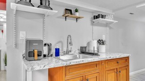 Una cocina moderna con cafetera integrada, un lavamanos y armarios de madera.
