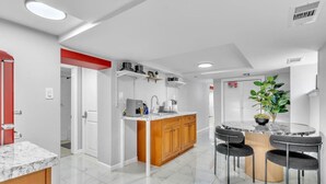 Una cocina moderna con una isla central, armarios de madera y un comedor con cuatro sillas.