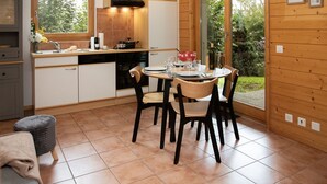 A modern kitchen with a dining area, wooden walls, and large windows. - Lovely apartment for 3 guests with WIFI, TV and terrace (Ovronnaz)