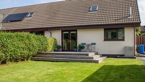 A two-story house with a tiled roof, a front porch with steps, and a small garden area. - Beautiful  villa for 5 guests with WIFI and TV (Isle Of Skye)