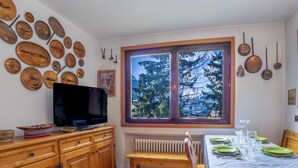 Een gezellige keuken met houten kasten, een eettafel gedekt voor vier personen en een groot raam met uitzicht op bomen.