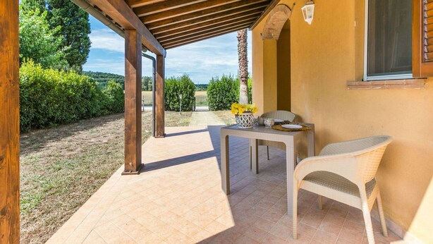 Ein Patio im Freien mit einer Holz-Pergola, einem Tisch mit Stühlen und Blick auf die umliegende Landschaft.