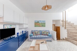 Uma sala de estar com televisão, sofá e um quadro na parede.
