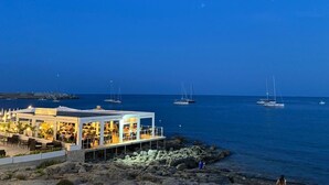Ein Restaurant am Meer mit Außenplätzen und Blick auf den Ozean, das an einer felsigen Küste liegt.