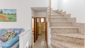 Eine Treppe führt zu einer zweiten Etage, ein Gang mit einer Tür und ein farbenfrohes Gemälde an der Wand.