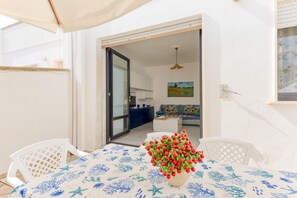 Un coin repas avec une table dressée pour deux personnes, une plante en pot et une vue sur la cuisine.