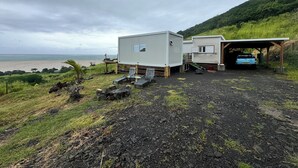 A beachfront property with a covered parking area, a small building, and a beach view.