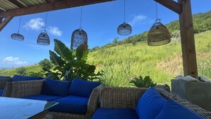 A covered outdoor seating area with wicker furniture and hanging wicker lamps.