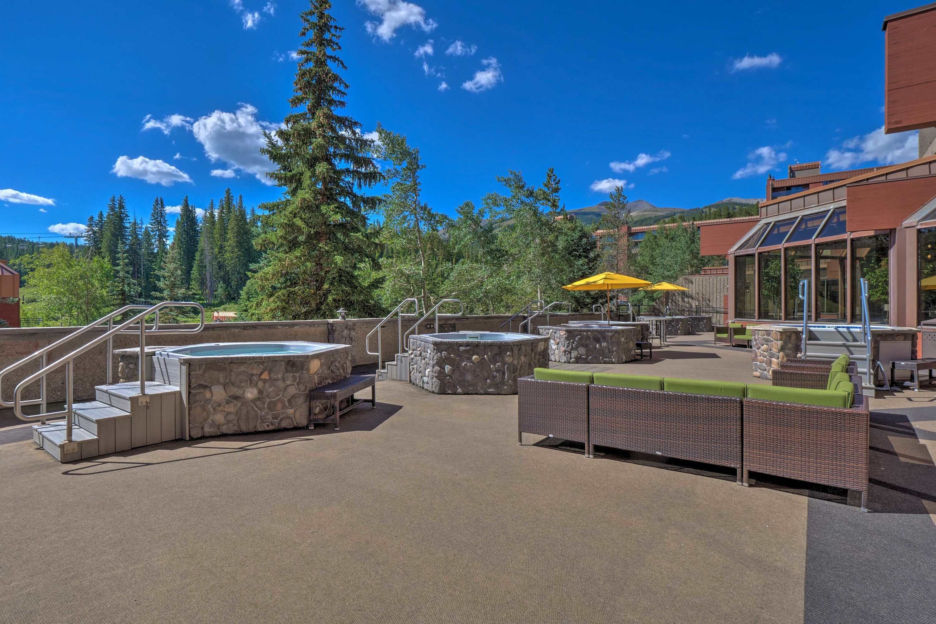 An outdoor patio with hot tubs, seating areas, and a staircase leading to an upper level.