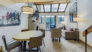 A modern interior with a round dining table, chairs, a sofa, and a TV.