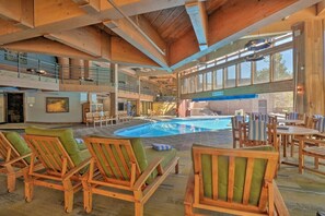 A spacious indoor pool area with wooden lounge chairs and tables, large windows, and a high ceiling. - Slope-side Studio, Peak 9, Dog Friendly, Kitchen (Breckenridge)