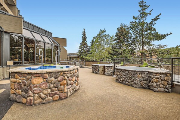 An outdoor pool area with stone walls and a glass-enclosed building in the background.