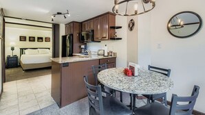 A compact hotel room with a kitchenette, a dining area with a round table and chairs, a bed with a nightstand, and a large mirror on the wall. - Ski In, Ski Out Studio, Peak 9 Views From Balcony, Hot Tubs, Beaver Run (Breckenridge)