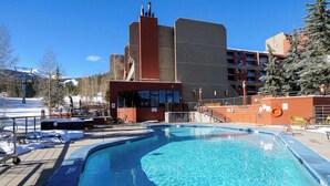 A swimming pool with a view of a building with a red facade and a ski lift in the background. - Ski In, Ski Out Studio, Peak 9 Views From Balcony, Hot Tubs, Beaver Run (Breckenridge)