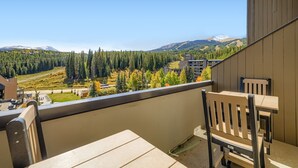 A balcony with a view of a mountainous landscape, a wooden table, and two chairs. - Ski In/Ski Out 2BR Condo, Dog Friendly, Hot Tubs at Beaver Run (Breckenridge)