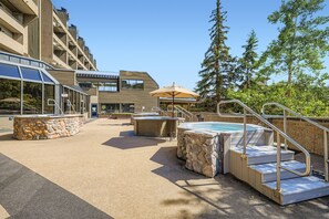 Een dakterras met een zwembad, stenen zitplaatsen, een jacuzzi en een overdekte zithoek.