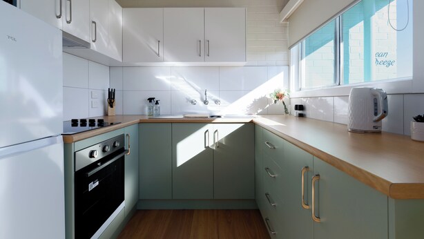 Una cocina moderna con armarios blancos, horno empotrado y encimera de madera.