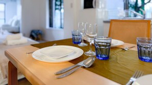 A dining table set with plates, cutlery, and blue glassware, with a view of a living area in the background.