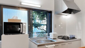 A compact kitchen with a microwave, toaster, sink, and stove.