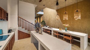A modern kitchen with a central island, wooden staircase, and pendant lights. - Wazen Retreat Villa Da Nang (Da Nang)