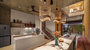 A modern kitchen with a central island, wooden cabinets, and pendant lights. - Wazen Retreat Villa Da Nang (Da Nang)