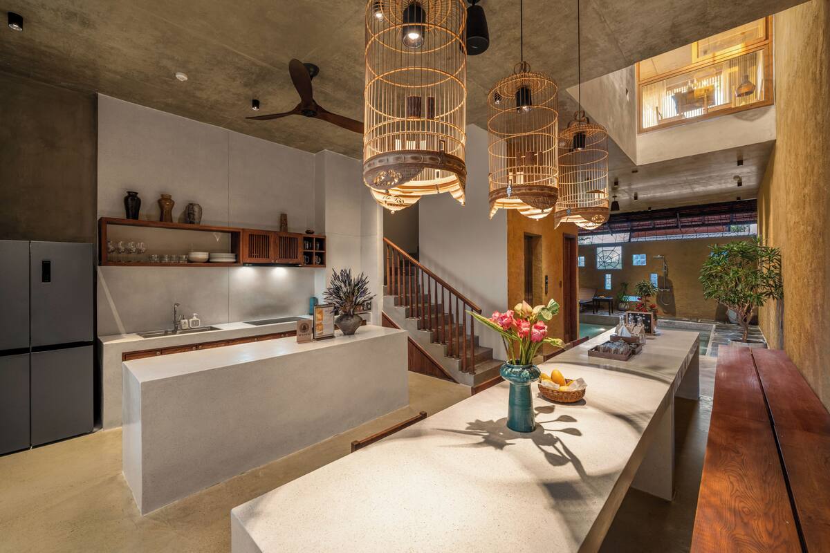 Une cuisine moderne dotée d’un îlot central, de meubles en bois et de luminaires suspendus.