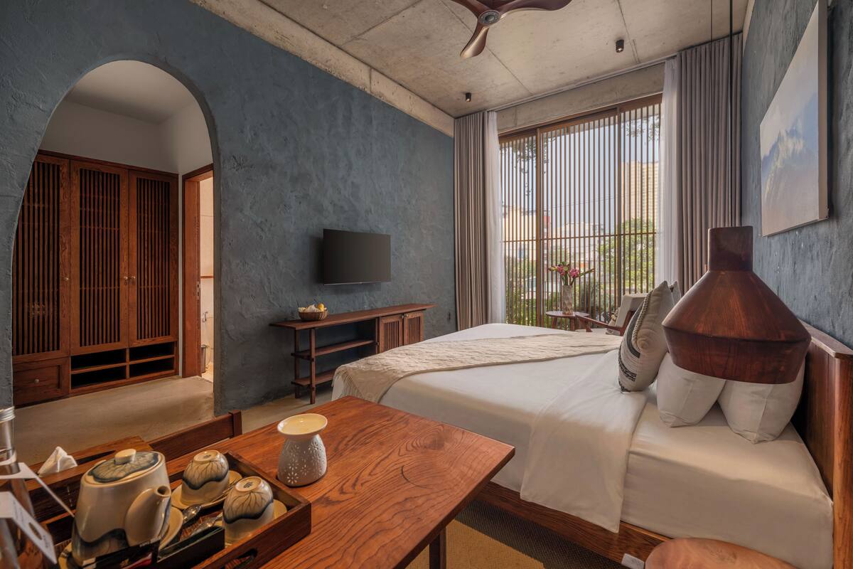 Une chambre à coucher avec un lit, des meubles en bois, une télévision et une fenêtre avec des rideaux.