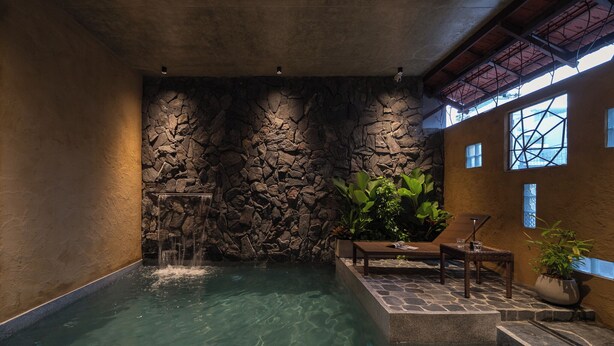 A spa area with a stone wall, a small waterfall, and a seating area with a potted plant. - Wazen Retreat Villa Da Nang (Da Nang)