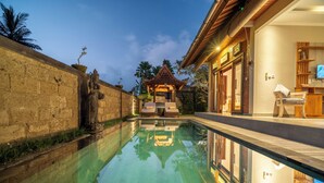 A serene pool area with a traditional gazebo, stone walls, and a well-lit interior space. - Alisa Private Villa (Ubud)