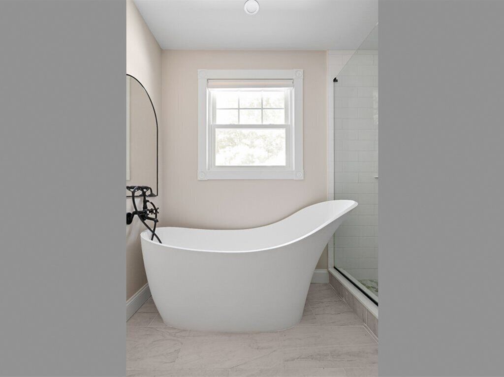 A modern bathroom with a freestanding bathtub, a window, and a shower area.