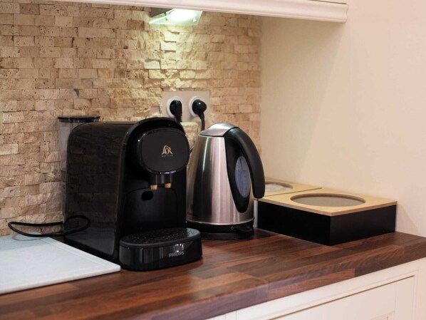 Eine Küche mit Kaffeemaschine, Wasserkocher und Kaffee-Kapselstation.